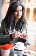 Young woman drinking coffee in a cafe outdoors. 