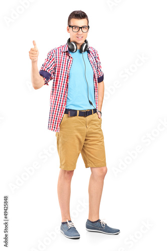 Photo: Full length portrait of a young man with headphones giving a thu Full length portrait of a young man with headphones giving a thu