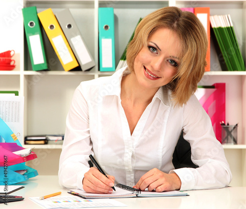 Photo: Beautiful young business woman working in office Beautiful young business woman working in office