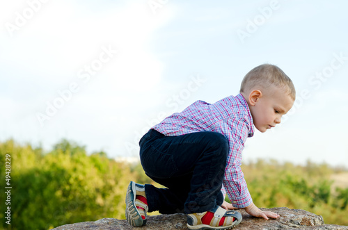 Photo: Little boy exploring climbing a rock Little boy exploring climbing a rock