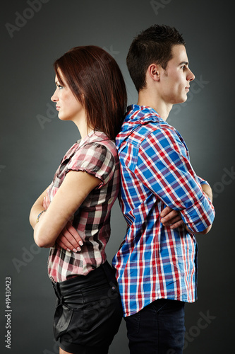 Photo: Portrait of sad young couple standing back to back Portrait of sad young couple standing back to back