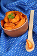 Appetizing village potatoes in bowl on blue fabric close-up