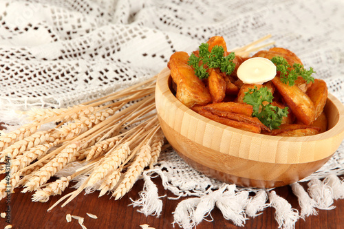 Photo: Appetizing village potatoes in bowl on wooden table close-up Appetizing village potatoes in bowl on wooden table close-up