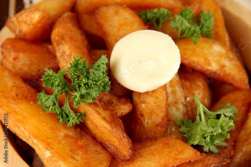 Photo: Appetizing village potatoes in bowl on wooden table close-up Appetizing village potatoes in bowl on wooden table close-up