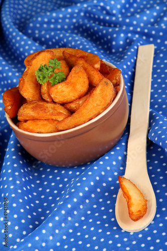 Photo: Appetizing village potatoes in bowl on blue fabric close-up Appetizing village potatoes in bowl on blue fabric close-up