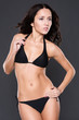 Young woman with black bikini in front of grey background