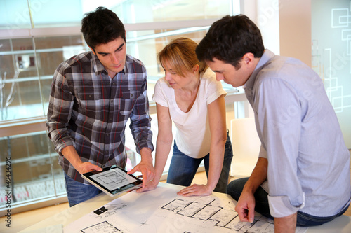 Photo: Startup business team working on blueprint Startup business team working on blueprint