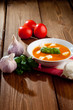 Tomato soup with shredded cheese in ceramic bowl on a wooden tab