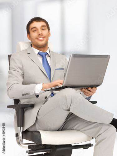 Photo: young businessman sitting in chair with laptop young businessman sitting in chair with laptop