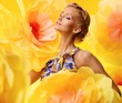 Beautiful young woman among big yellow flowers
