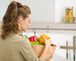 Young housewife examines purchases after shopping in kitchen
