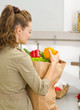 Young housewife examines purchases after shopping in kitchen. re
