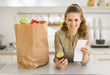 Smiling housewife examines purchases and check after shopping