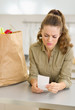 Concerned young housewife examines check after shopping