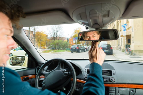 Photo: Taxi driver is looking in the driving mirror Taxi driver is looking in the driving mirror