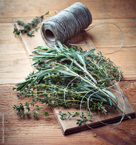 Photo: Bunch of thyme and rosemary on wooden board Bunch of thyme and rosemary on wooden board