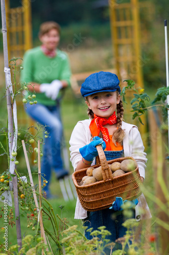 Photo: Gardening - girl helping mother in the vegetable garden Gardening - girl helping mother in the vegetable garden