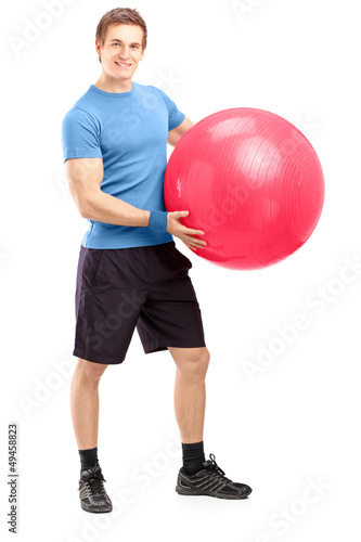 Photo: Full length portrait of a young male athlete holding a pilates b Full length portrait of a young male athlete holding a pilates b