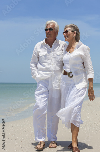 Photo: Happy Senior Couple Walking by Sea on Tropical Beach Happy Senior Couple Walking by Sea on Tropical Beach