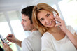 Couple using smartphone, sitting back to back