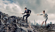 Two businessmen pulling rope atop of mountain