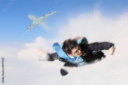 Photo: Young businessman flying with parachute on back Young businessman flying with parachute on back
