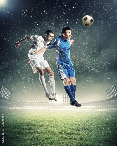 Photo: two football players striking the ball two football players striking the ball