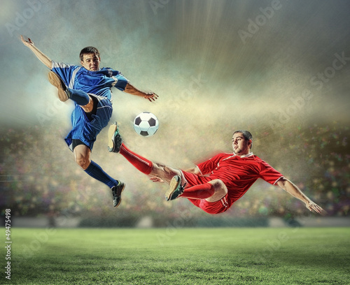 Photo: two football players striking the ball two football players striking the ball