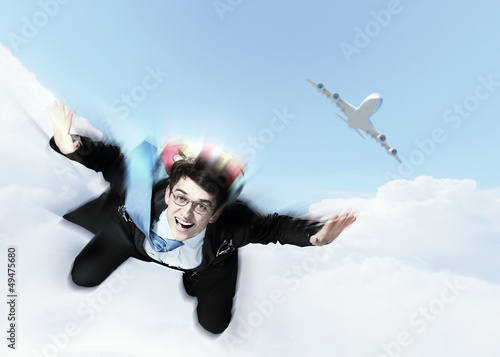 Photo: Young businessman flying with parachute on back Young businessman flying with parachute on back
