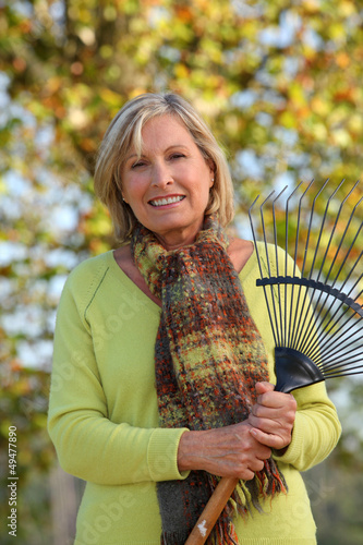 Photo: Woman raking leaves in a yard Woman raking leaves in a yard