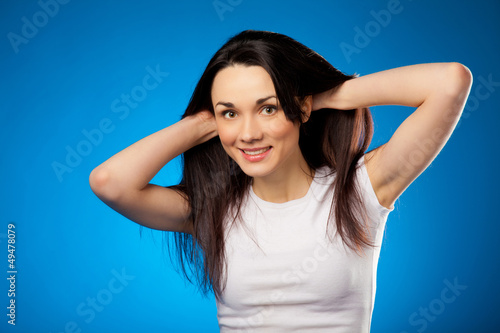 Photo: smiling beautiful brunette girl in white t-shirt over blue backg smiling beautiful brunette girl in white t-shirt over blue backg