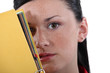 Shy woman hiding behind folder