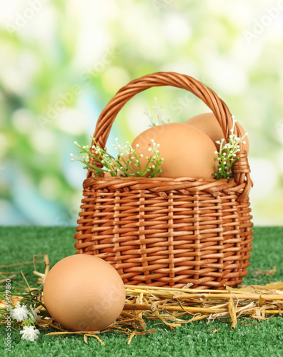 Photo: Eggs in basket on grass on natural background Eggs in basket on grass on natural background