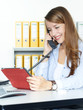 Female office assistant has a call and checks notes on tablet pc