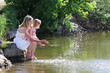 mother and her little daughter squirting water at the lake