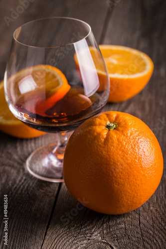 Photo: Orange with glass of whiskey or brandy on wooden table. Orange with glass of whiskey or brandy on wooden table.