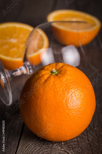 Photo: Orange with empty glass on wooden surface. Orange with empty glass on wooden surface.