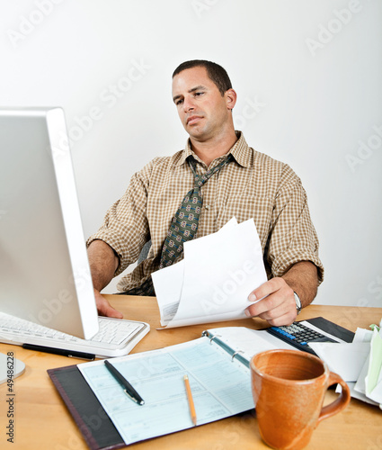 Photo: Tired Young Man at Desk Paying Bills Tired Young Man at Desk Paying Bills
