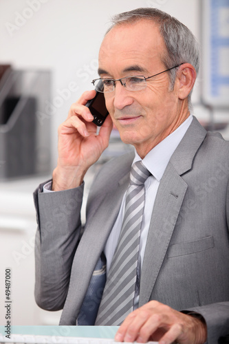 Photo: 65 years old man wearing a grey suit and calling 65 years old man wearing a grey suit and calling