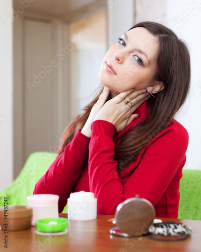 Photo: young woman uses cosmetic cream young woman uses cosmetic cream