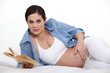Pregnant woman stroking her pregnant belly while reading