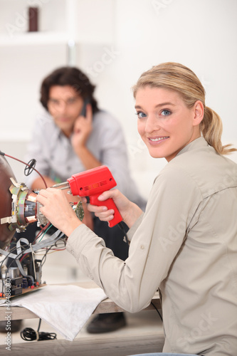 Photo: A woman fixing a TV. A woman fixing a TV.