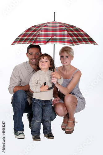 Photo: Young family sheltering under an umbrella Young family sheltering under an umbrella