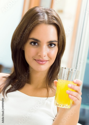 Photo: Cheerful young woman with orange juice at home Cheerful young woman with orange juice at home