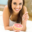Portarit of young woman eating grapefruit at home
