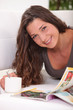 Woman laying on sofa with cup of coffee and magazine