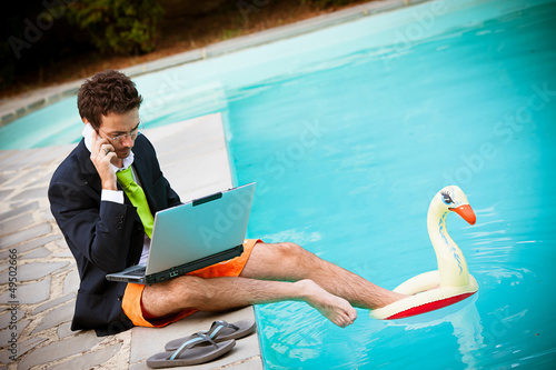 Photo: Funny Young Businessman with SwimmingTrunks next to the Pool Funny Young Businessman with SwimmingTrunks next to the Pool