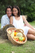 Couple sitting in the grass with fruit basket