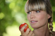 a blonde woman eating an apple