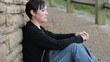 Sad woman sitting against a wall 2